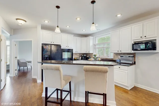 a kitchen with stainless steel appliances granite countertop a stove a sink a refrigerator a microwave oven a stove a dining table and chairs