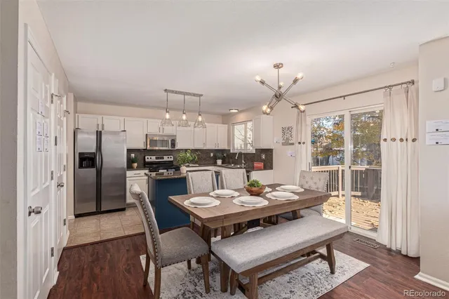 a kitchen with a refrigerator a dining table and chairs