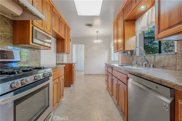 a kitchen with stainless steel appliances granite countertop a sink stove and cabinets