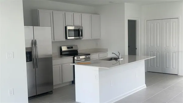 a kitchen with stainless steel appliances a refrigerator a sink a stove a microwave a counter space and cabinets