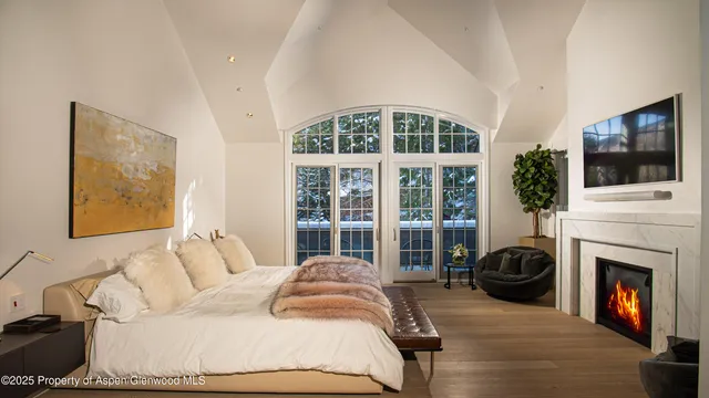 a bedroom with a bed a fireplace and a flat screen tv