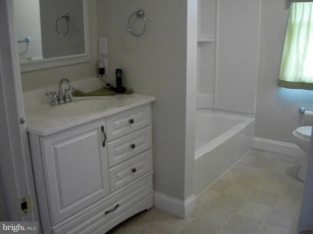 a bathroom with a bathtub sink vanity and toilet