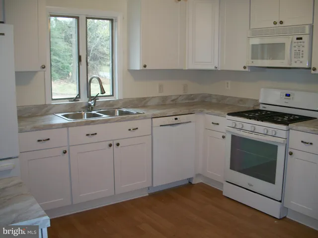 a kitchen with granite countertop white cabinets stainless steel appliances a sink and a window
