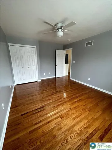 an empty room with wooden floor and fan