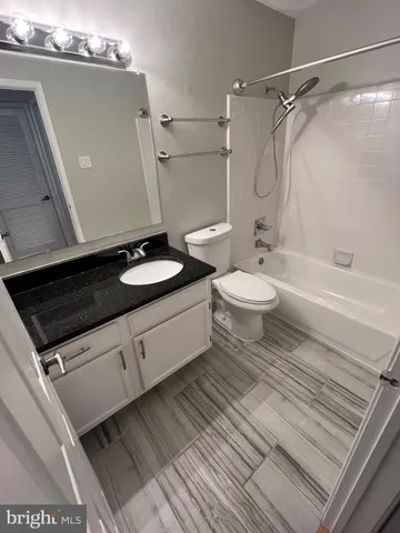 a bathroom with a granite countertop sink toilet a shower and a mirror