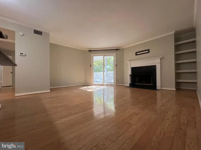 an empty room with wooden floor fireplace and windows