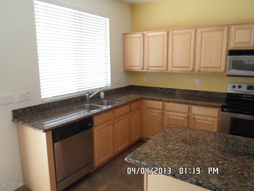 4047 East Agave Road Phoenix, AZ 85044 - Photo 6 of 20 a kitchen with granite countertop a sink stove and cabinets