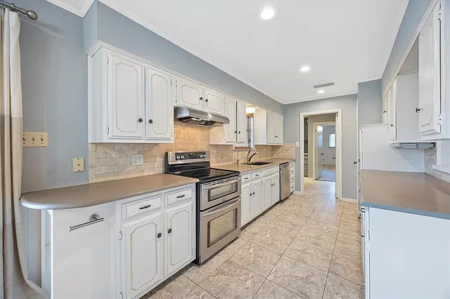 a kitchen with granite countertop a sink stove and cabinets