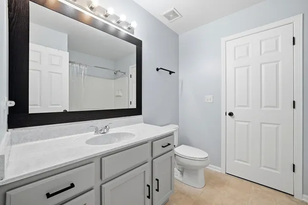 a bathroom with a toilet a sink a vanity and mirror