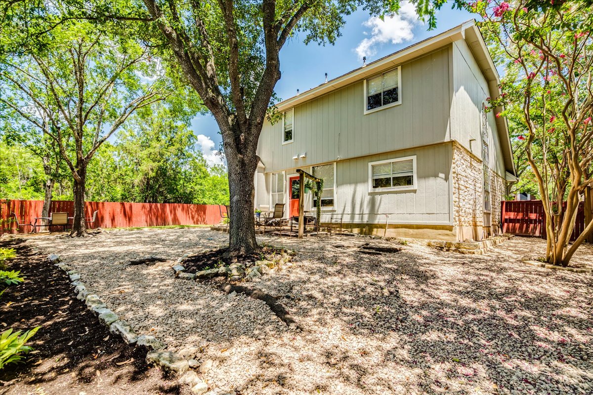9300 Tea Rose Trail Austin, TX 78748 - Photo 32 of 33 A private, gravel-filled yard, bordered by a vibrant red fence, offers ample outdoor space for leisure.