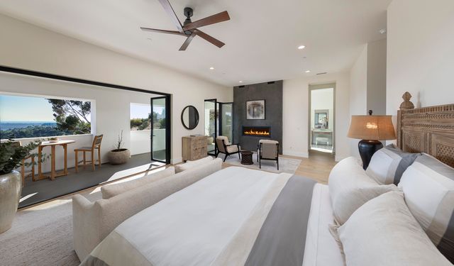 a bedroom with a large bed and a chandelier fan