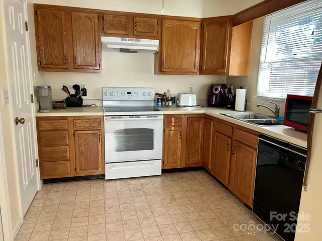 a kitchen with cabinets appliances a sink and a window