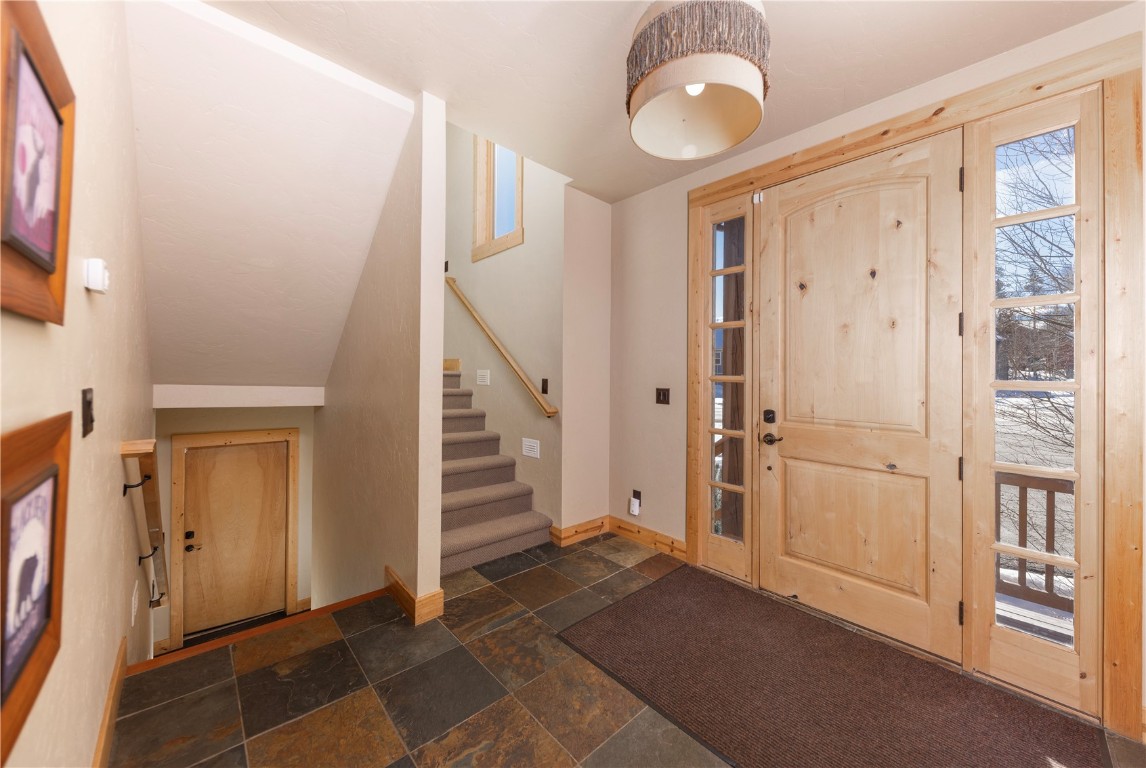 511 Ryan Gulch Road Wildernest, CO 80498 - Photo 26 of 37 Entryway featuring stone tile flooring, stairs, vaulted ceiling, and healthy amount of natural light