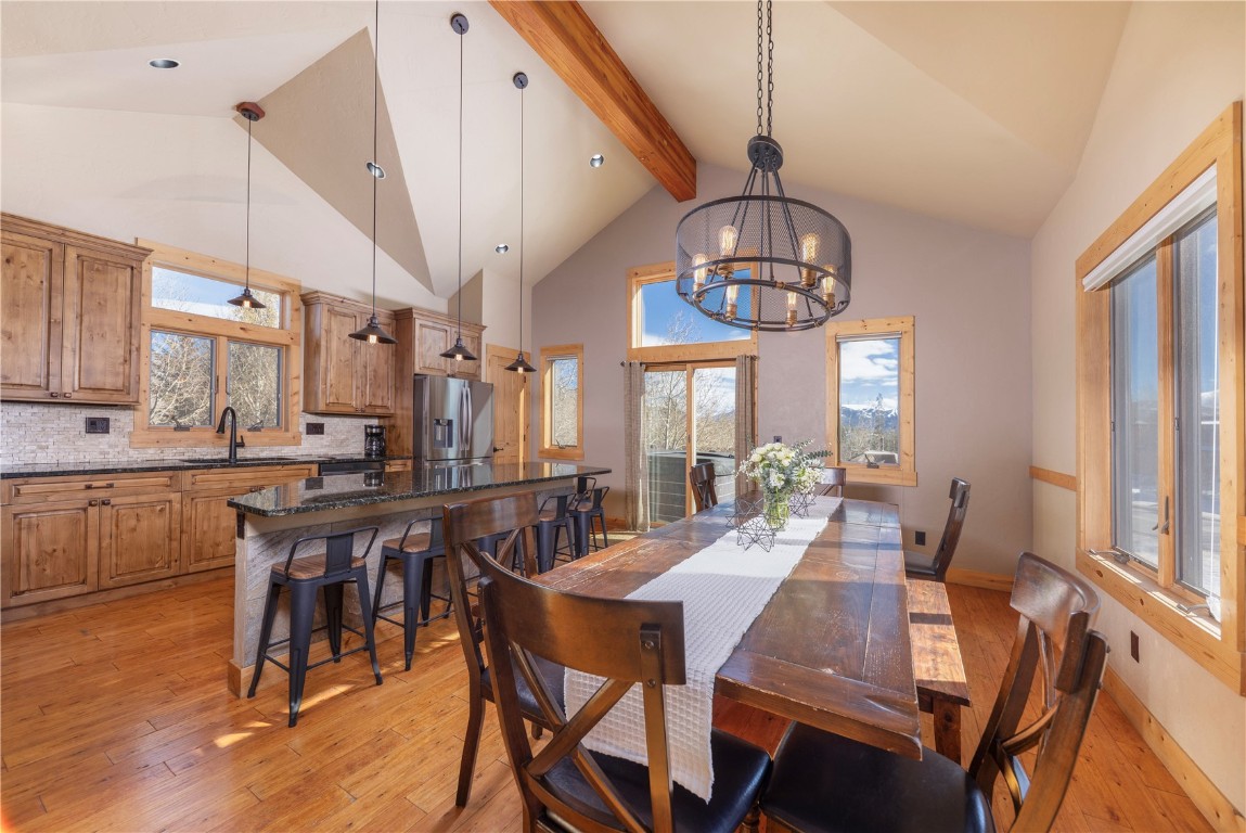 511 Ryan Gulch Road Wildernest, CO 80498 - Photo 4 of 37 Dining area featuring beamed ceiling, healthy amount of natural light, light wood-style flooring, a chandelier, and high vaulted ceiling