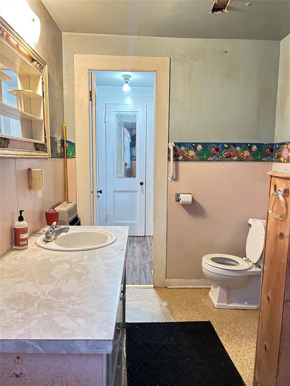 360 North Grafton Street Dublin, TX 76446 - Photo 16 of 24 This is your primary bathroom with a sink, formica counter, commode, storage, and vinyl flooring.