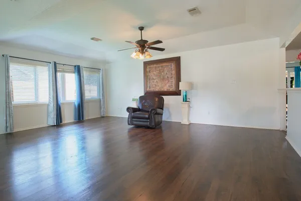 a view of empty room with wooden floor and fan