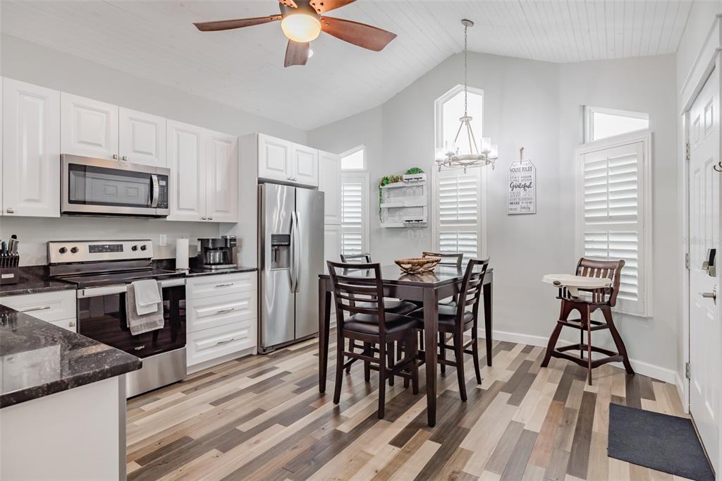 4021 Casa Court Hernando Beach, FL 34607 - Photo 14 of 37 a kitchen with stainless steel appliances kitchen island granite countertop a stove top oven a sink a dining table and chairs with wooden floor