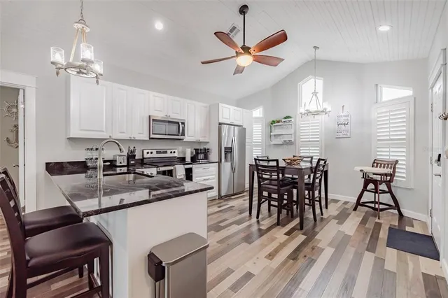 a kitchen with stainless steel appliances a dining table chairs stove refrigerator and cabinets