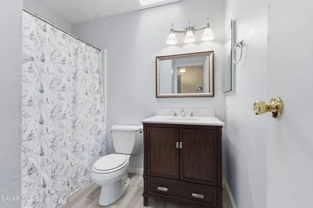 a bathroom with a toilet sink vanity and mirror
