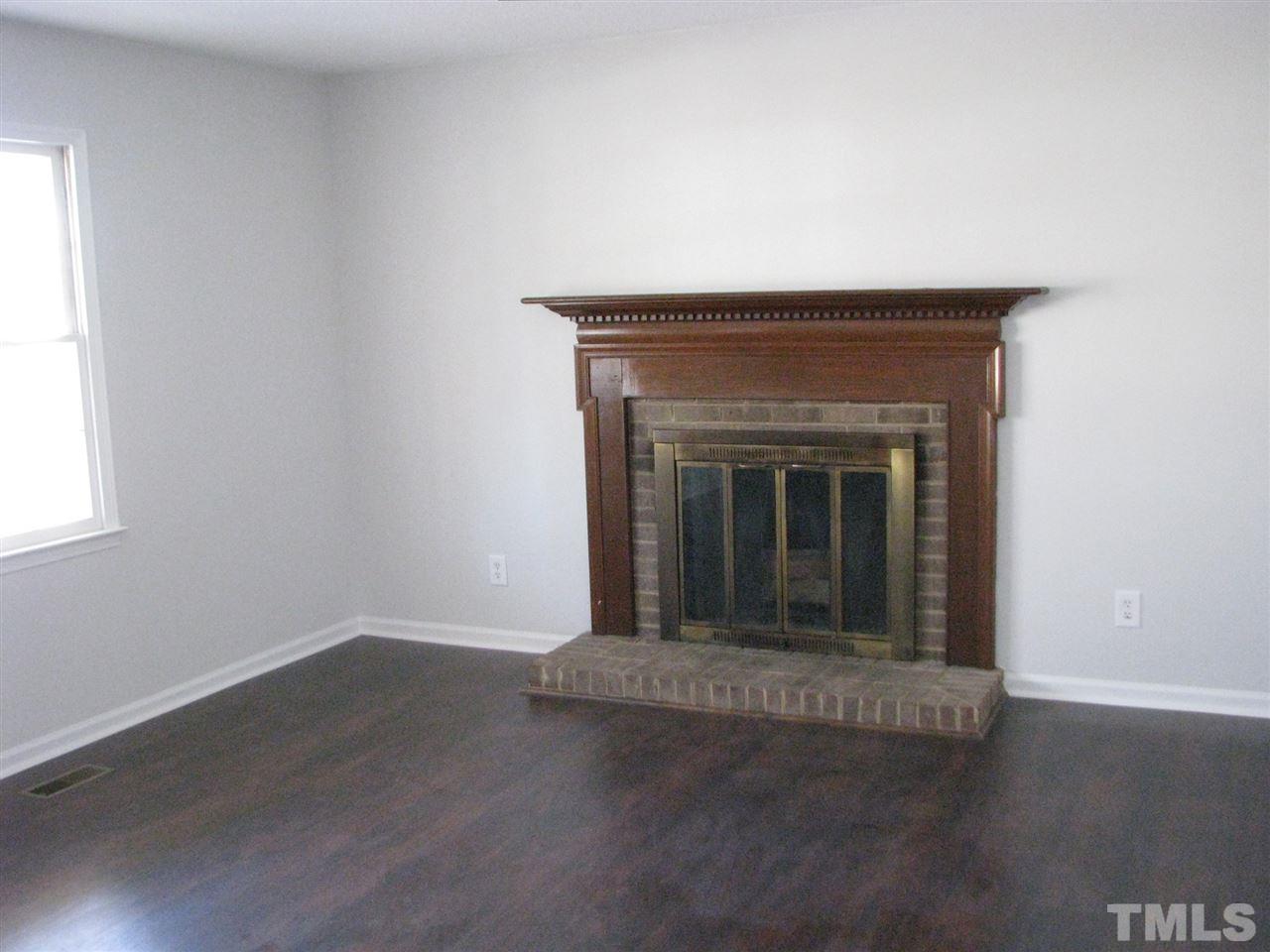 1101 Mockingbird Drive Raleigh, NC 27615 - Photo 3 of 21 an empty room with wooden floor and fireplace