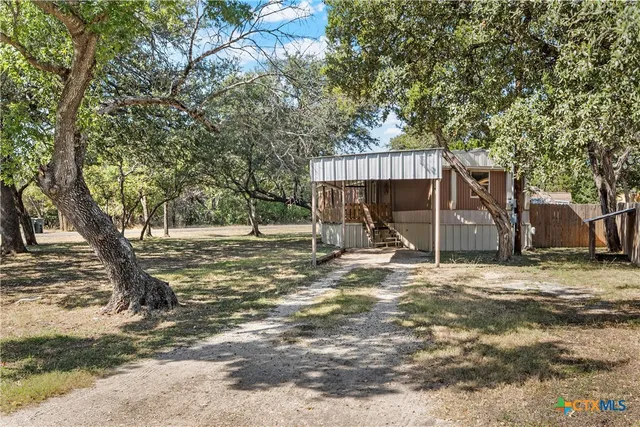 a view of a house with large tree and wooden fence