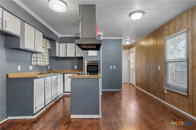 a kitchen with stainless steel appliances granite countertop a refrigerator a sink dishwasher a stove and white countertops with wooden floor