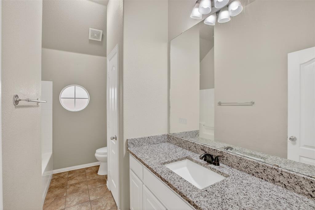 8208 Riversprings Drive Fort Worth, TX 76053 - Photo 20 of 26 a bathroom with a granite countertop sink a toilet and a mirror