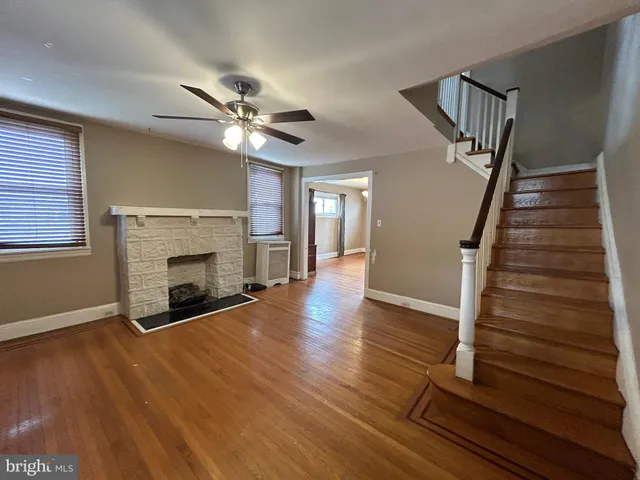 a view of an empty room with wooden floor fireplace and a window
