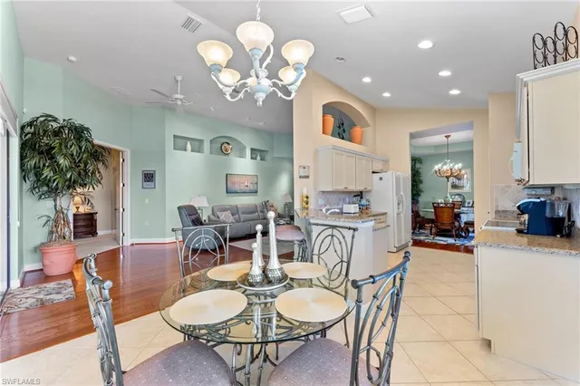 a dining room with wooden floor a chandelier a wooden table and chairs