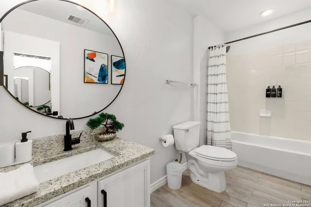 a bathroom with a granite countertop sink mirror vanity and toilet