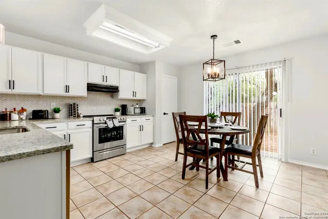 a kitchen with granite countertop a table chairs stove and cabinets