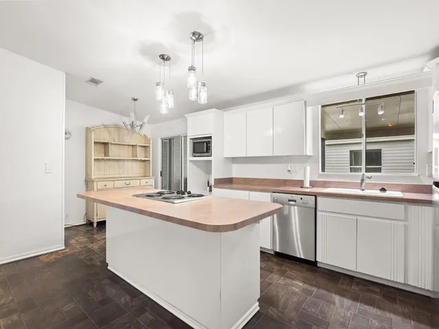 a kitchen with kitchen island granite countertop a sink cabinets and window