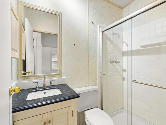 a bathroom with a granite countertop sink toilet and shower