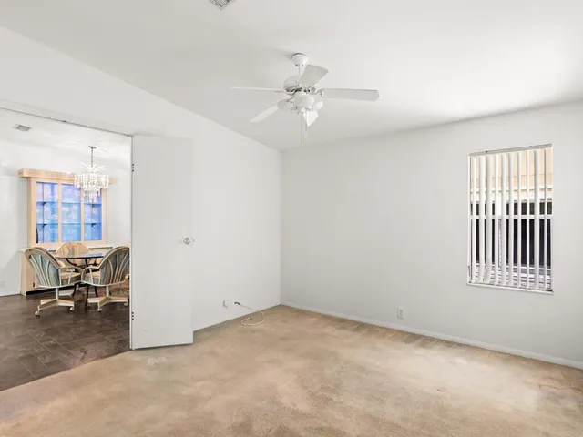 an empty room with windows and ceiling fan