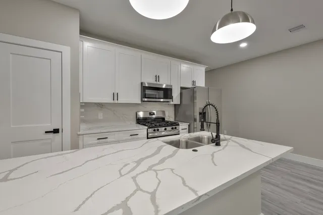 a kitchen with kitchen island granite countertop a sink cabinets a refrigerator and a stove