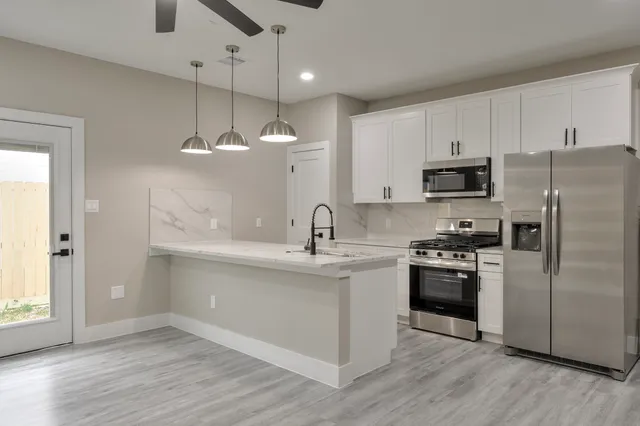 a kitchen with stainless steel appliances kitchen island hardwood floor sink and stove