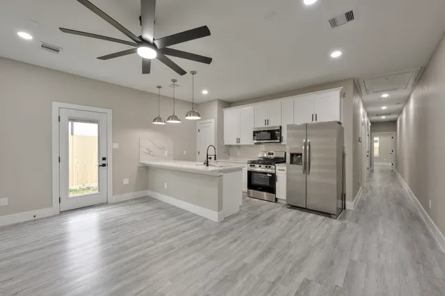 an empty room with wooden floor ceiling fan and windows