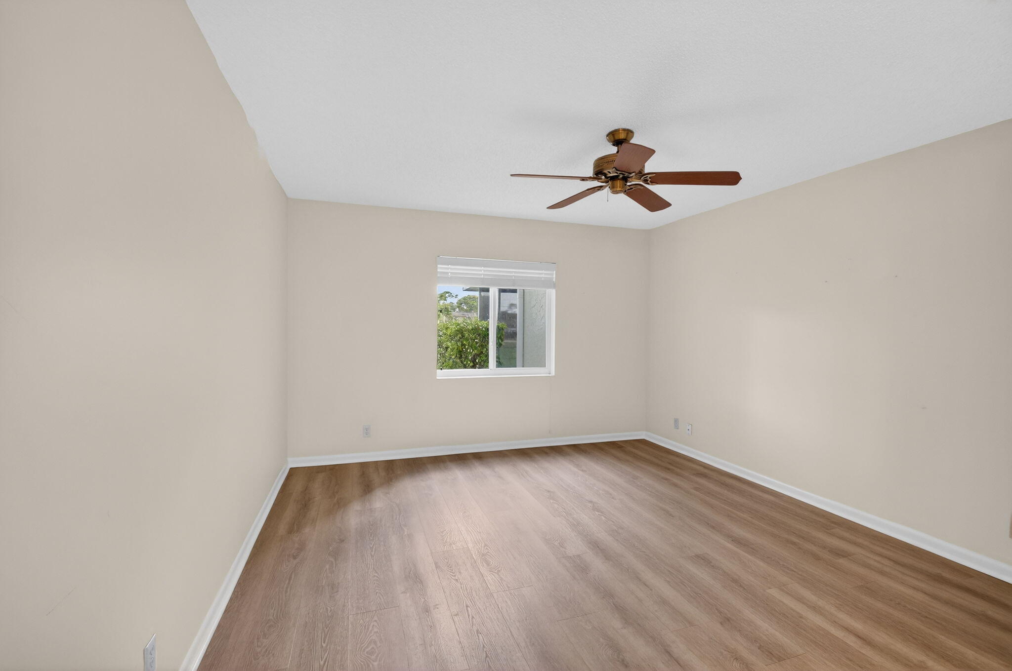 2840 Southwest 13th Street, Unit 103 Delray Beach, FL 33445 - Photo 24 of 72 an empty room with wooden floor ceiling fan and windows