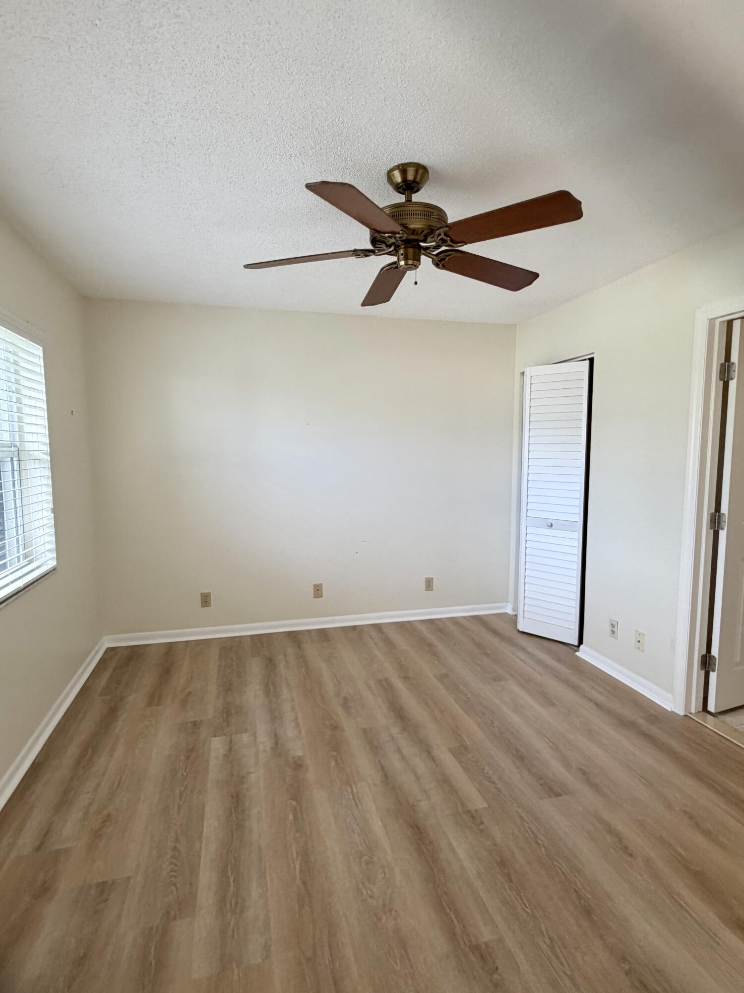2840 Southwest 13th Street, Unit 103 Delray Beach, FL 33445 - Photo 32 of 72 a view of a big room with wooden floor and a ceiling fan