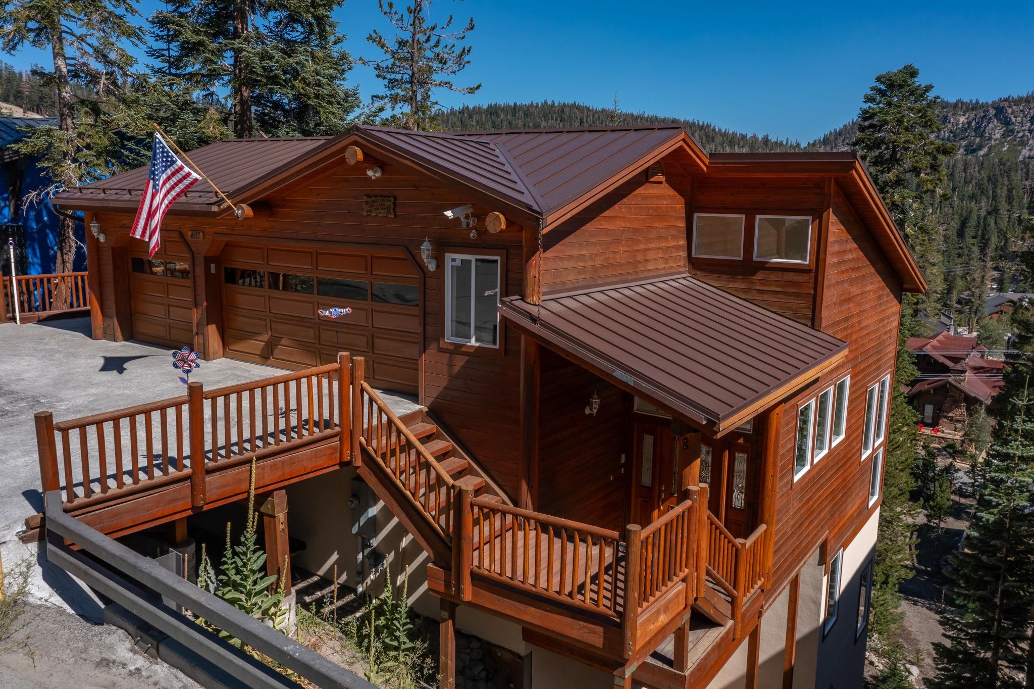 492 John Muir Road Mammoth Lakes, CA 93546 - Photo 1 of 33 Wood-sided exterior with a brown metal roof, two-car garage, and an elevated wood deck entry