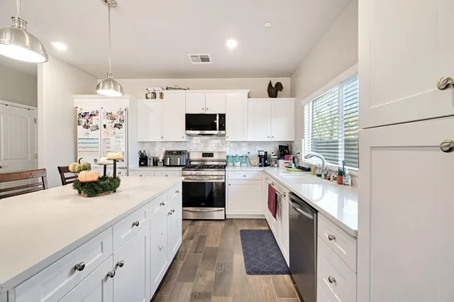 a kitchen with stainless steel appliances a sink dishwasher stove refrigerator and cabinets