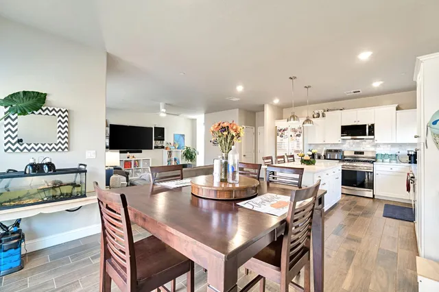 a kitchen with stainless steel appliances kitchen island granite countertop a stove a sink a dining table and chairs