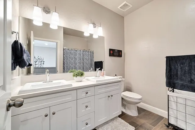 a bathroom with a double vanity sink mirror and toilet