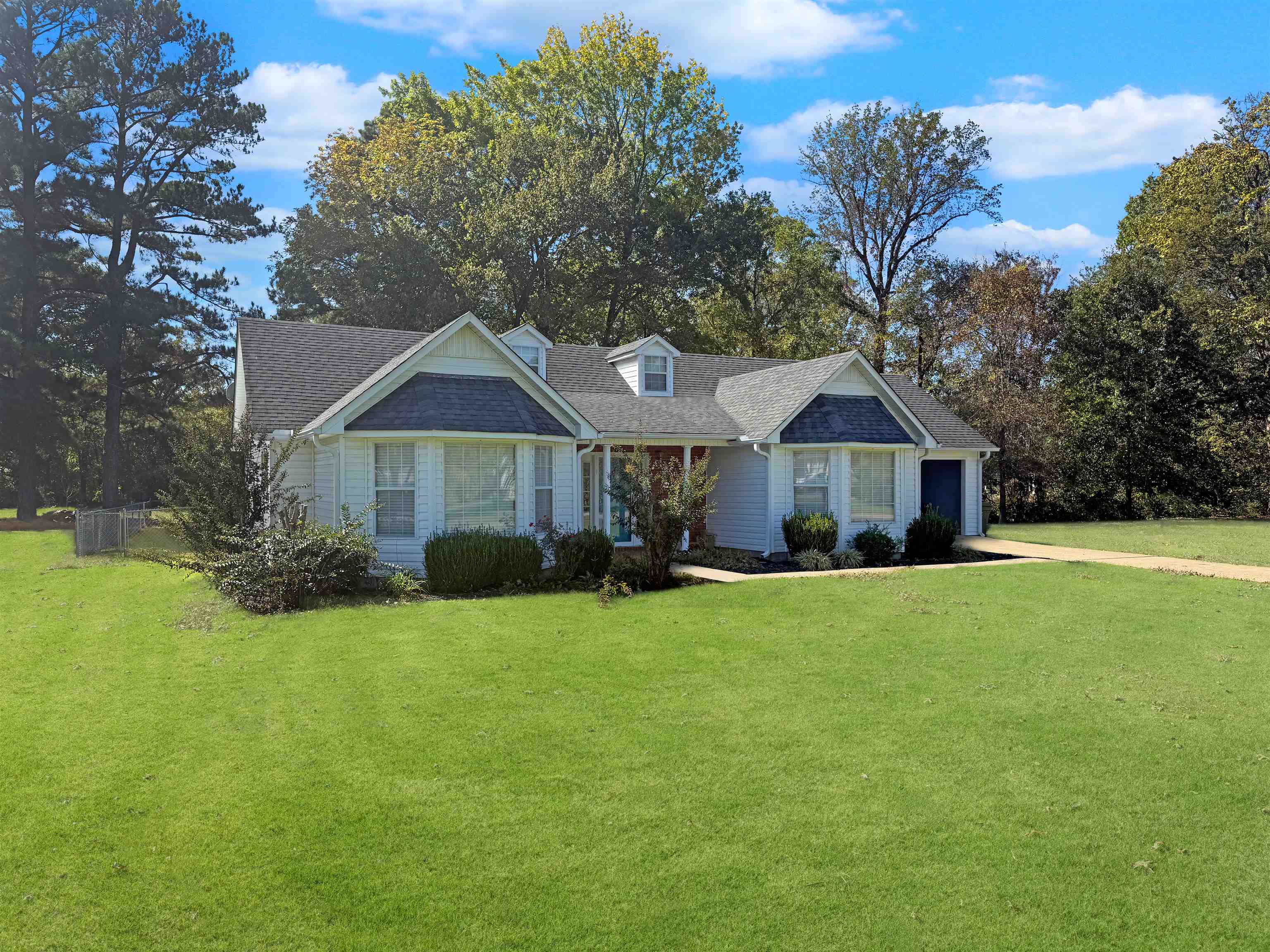 View of front of house featuring a front lawn, a shingled roof, a garage, and driveway