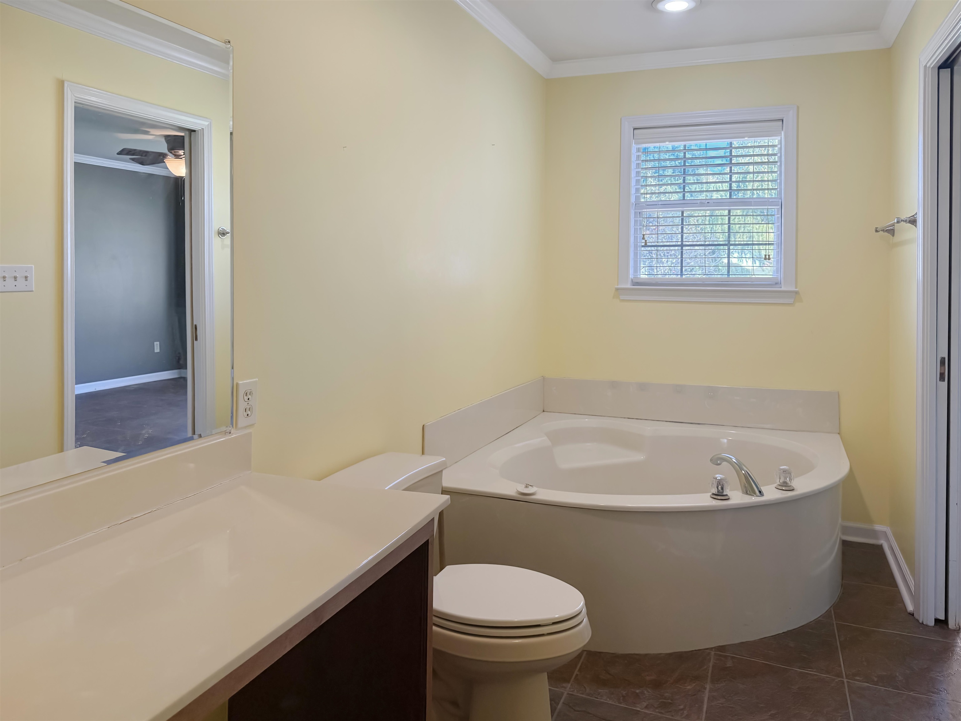 Full bathroom featuring a garden tub, ornamental molding, dark tile patterned floors, and vanity