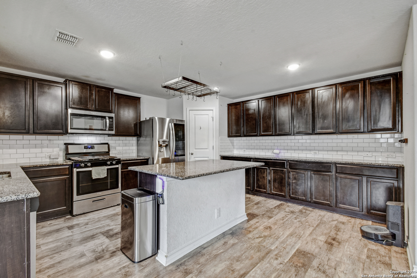 9627 Baytown Coast San Antonio, TX 78254 - Photo 7 of 22 a kitchen with stainless steel appliances granite countertop a stove top oven a sink dishwasher a refrigerator and a microwave