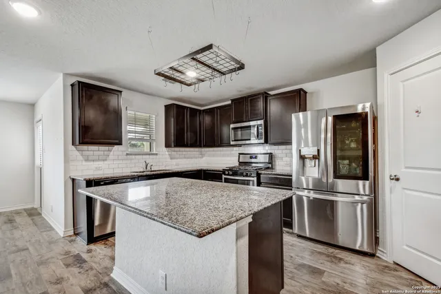 a kitchen with stainless steel appliances granite countertop a sink stove microwave and refrigerator