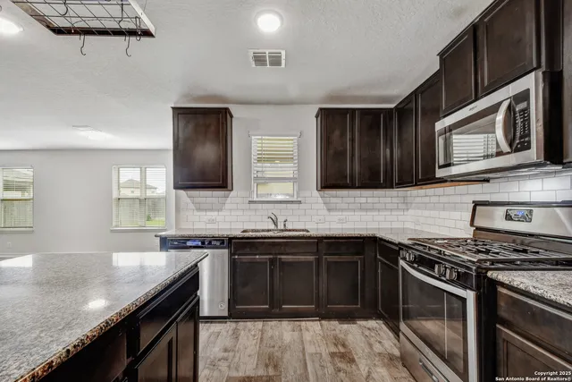 a kitchen with stainless steel appliances granite countertop a stove microwave and sink