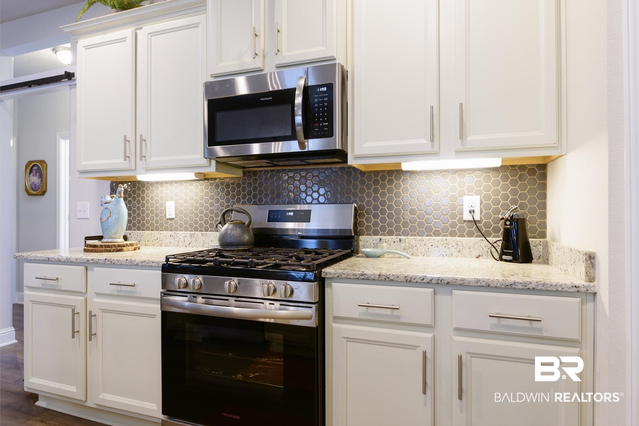 31751 Kestrel Loop Daphne, AL 36527 - Photo 8 of 21 Kitchen featuring stainless steel appliances, white cabinetry, tasteful backsplash, and light stone counters