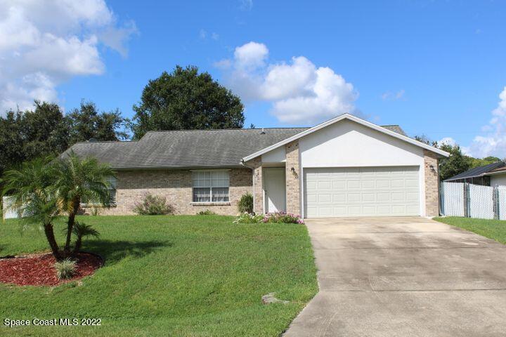 1324 Zanzibar Road Southeast Palm Bay, FL 32909 - Photo 1 of 18 a front view of a house with a yard and garage